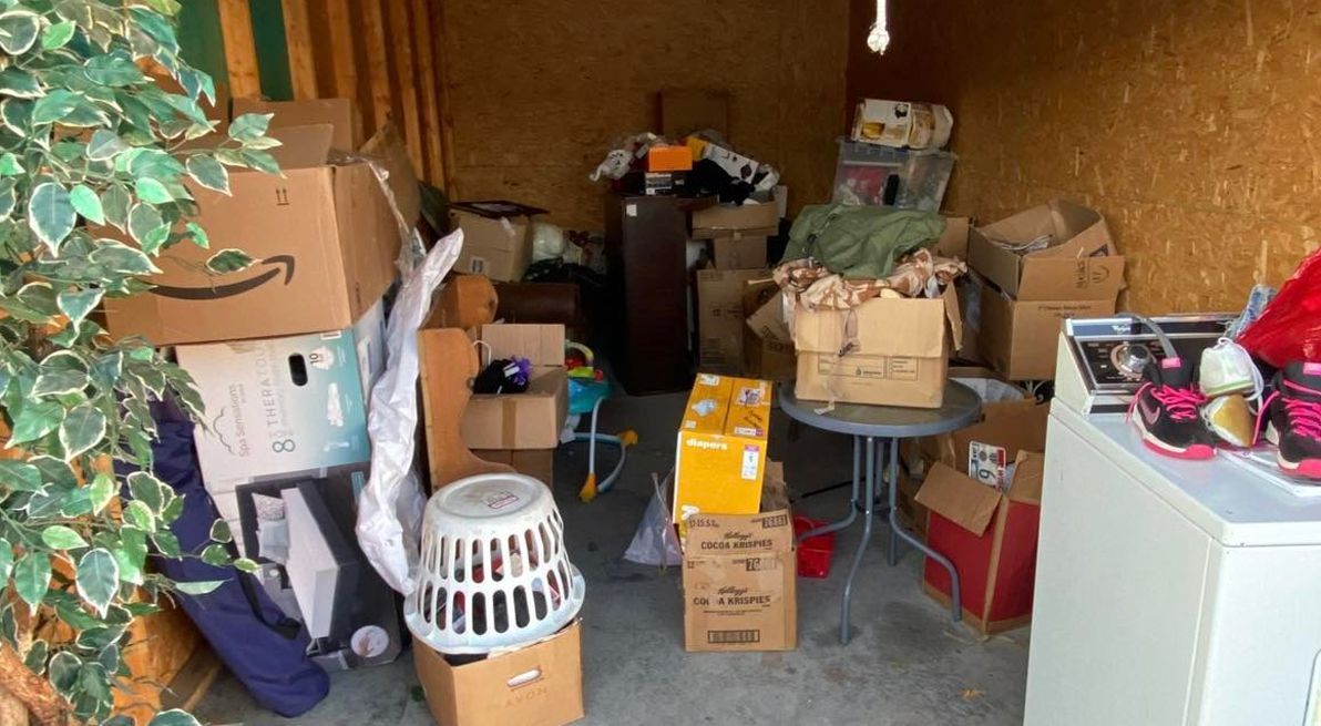 A shed filled with lots of boxes and a washer and dryer.