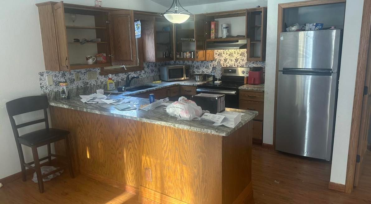 A kitchen with a stainless steel refrigerator , stove , sink and chair.