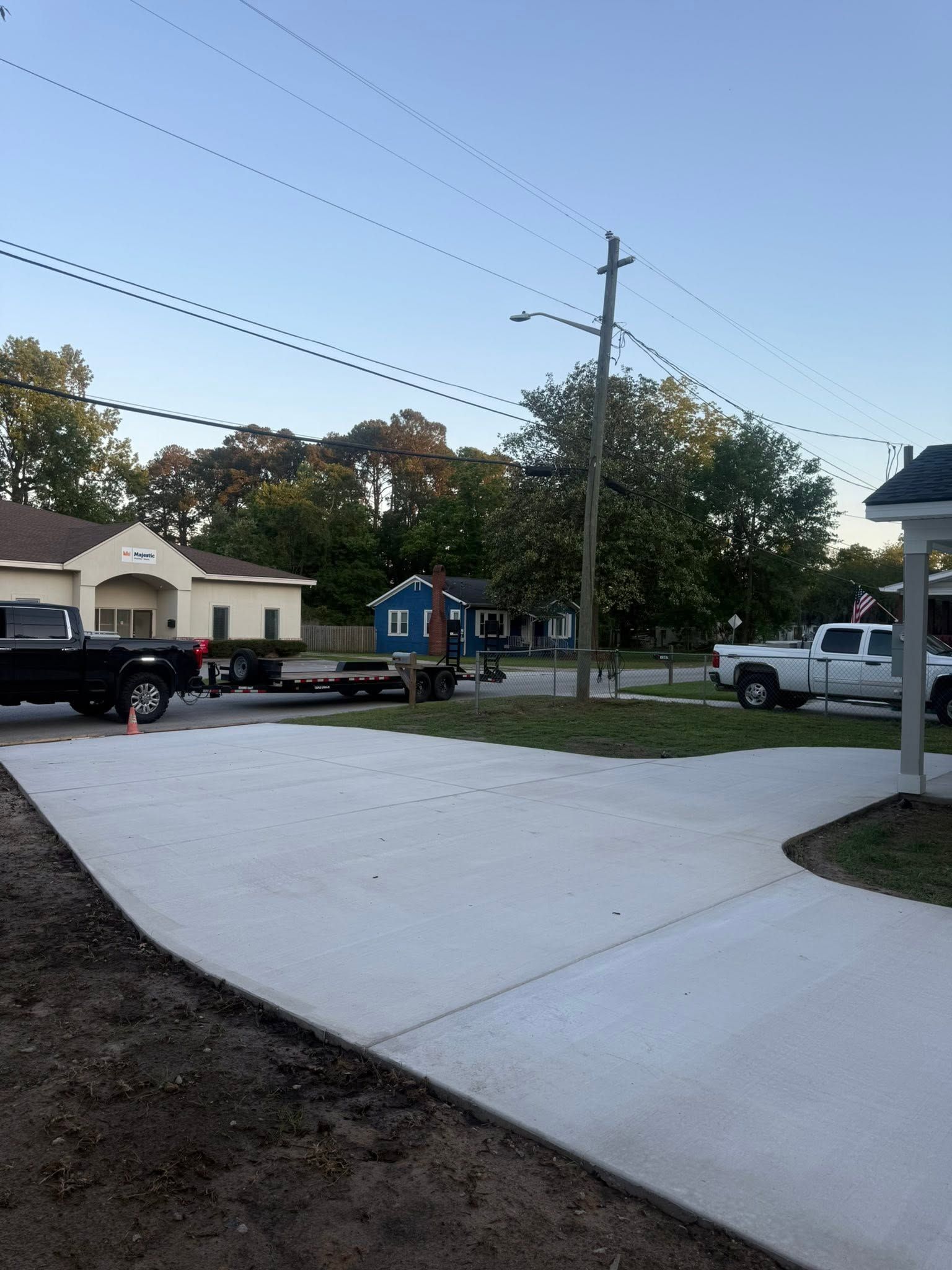 Suburban driveway with a black truck, blue dumpster, and utility pole at dusk