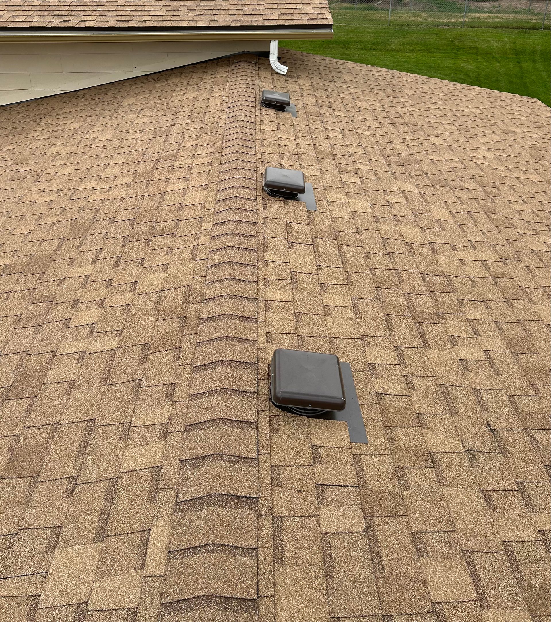 A brown shingled roof with three dark grey vents running in a line toward the peak.