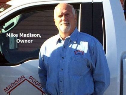 Mike Madison, owner of Madison Roofing, stands next to his truck; white truck, blue shirt.