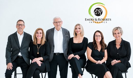 Five coworkers posing in a bright studio, two seated in front and three standing behind.
