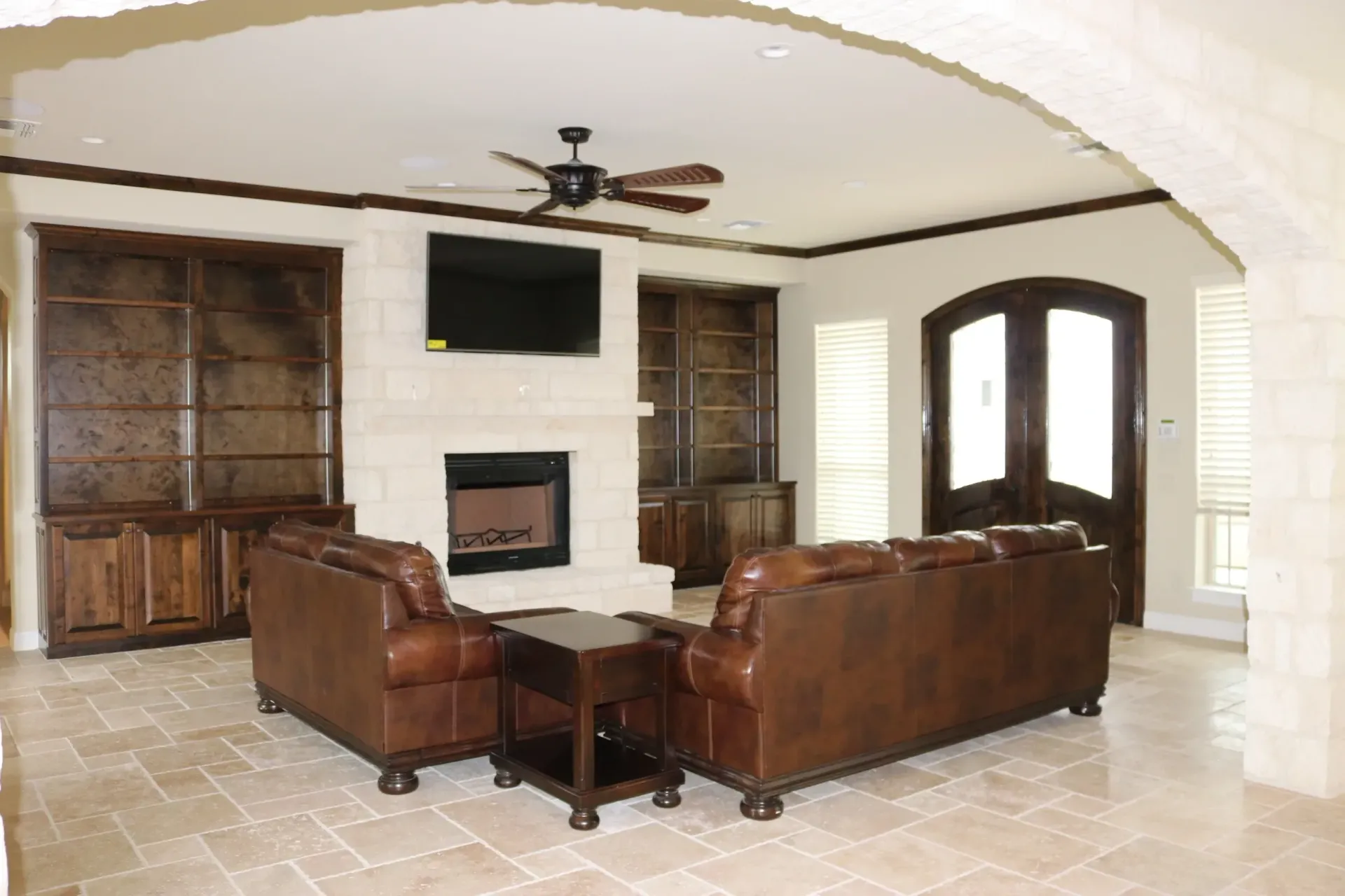 Living room with fireplace, leather furniture, built-in shelves, and dark wood trim.