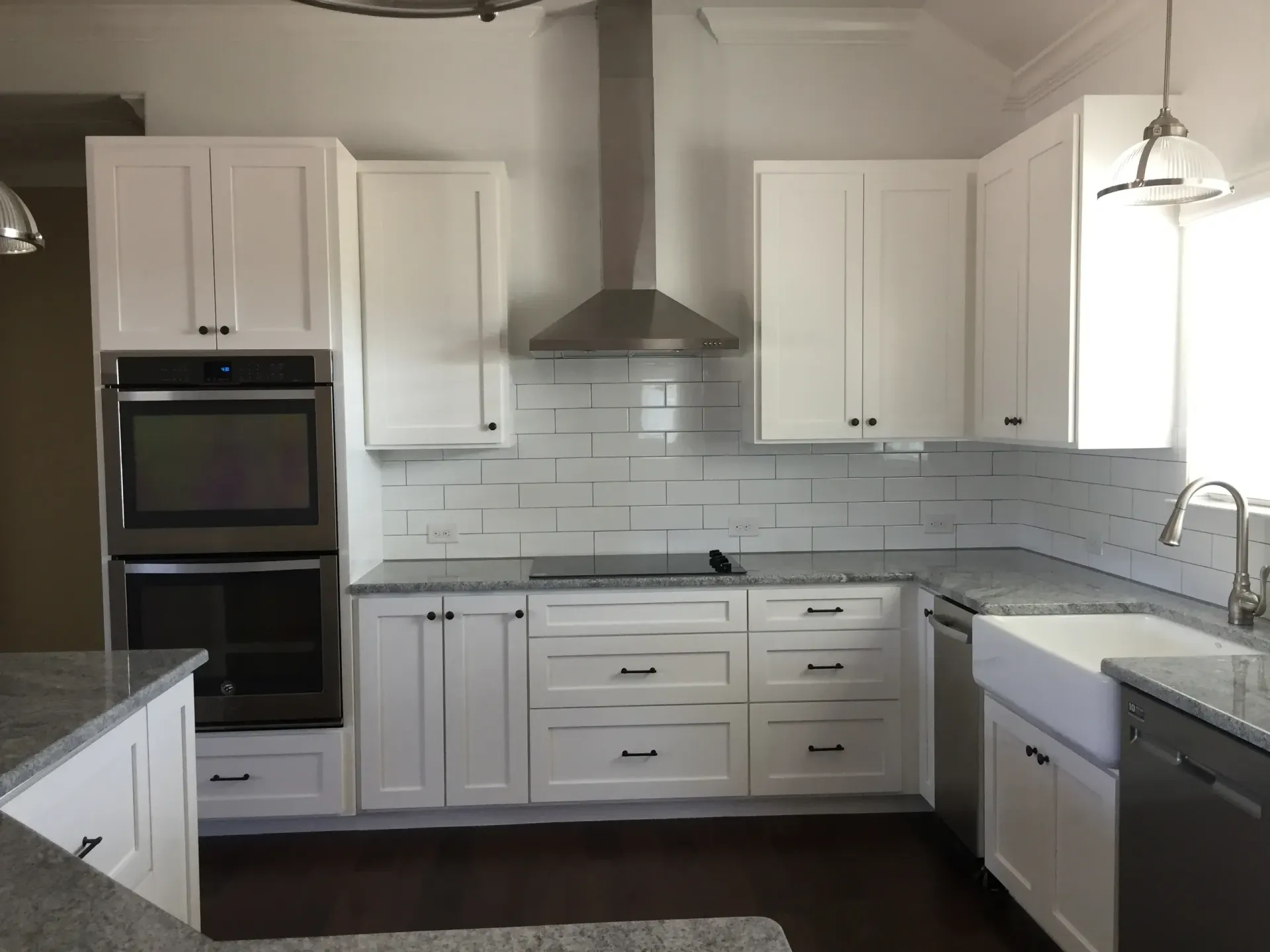 White kitchen with stainless steel appliances, white cabinets, and gray countertops.