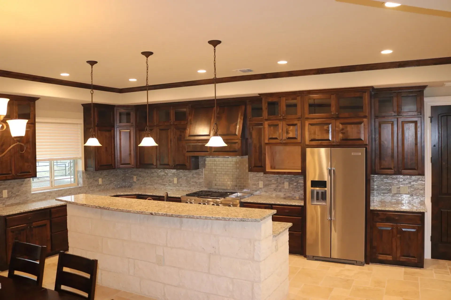 Dark wood kitchen with granite countertops, stainless steel appliances, and pendant lighting.