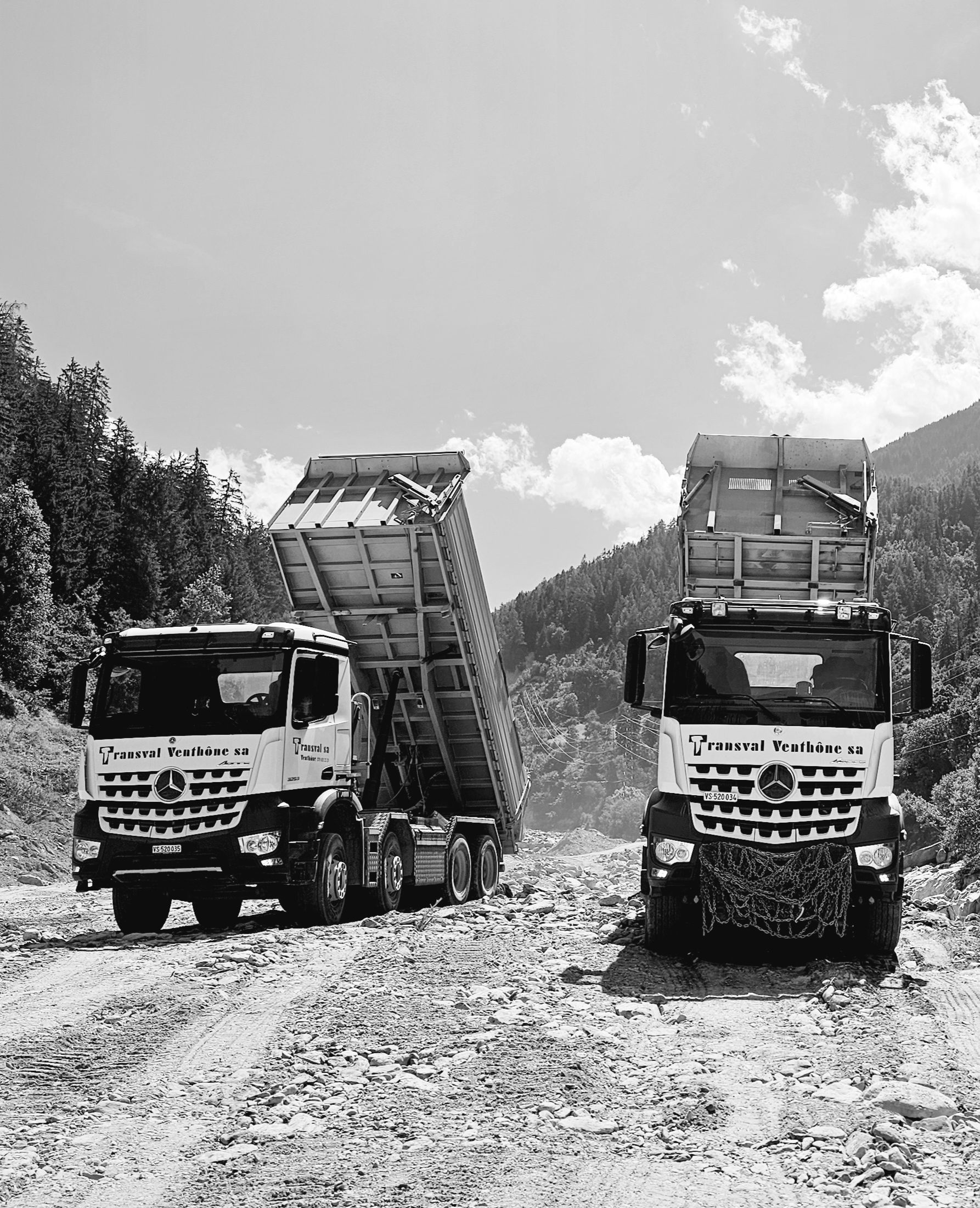 Deux camions à benne basculante sont garés l'un à côté de l'autre sur un chemin de terre.