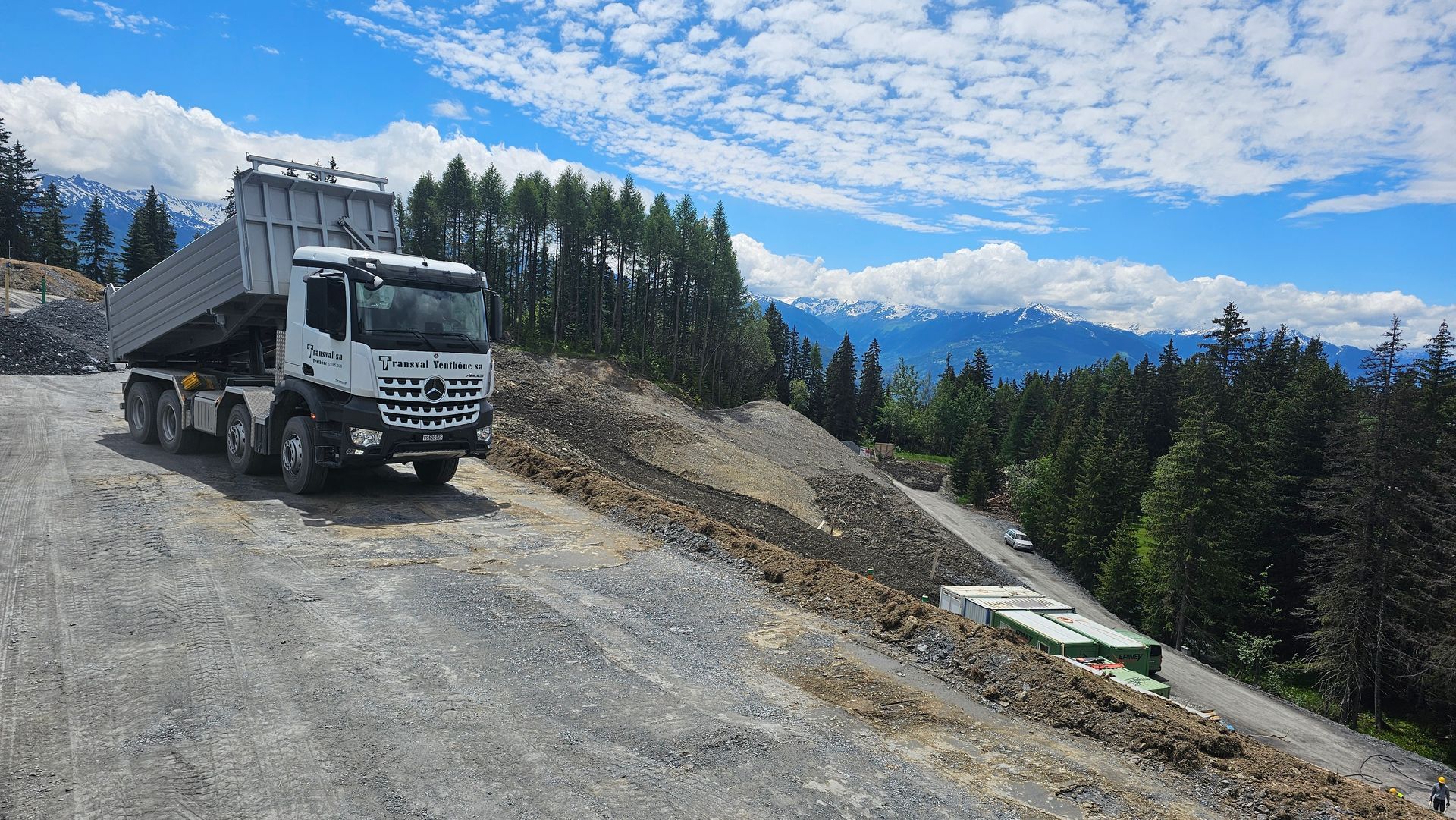 Un camion à benne basculante roule sur un chemin de terre dans les montagnes.