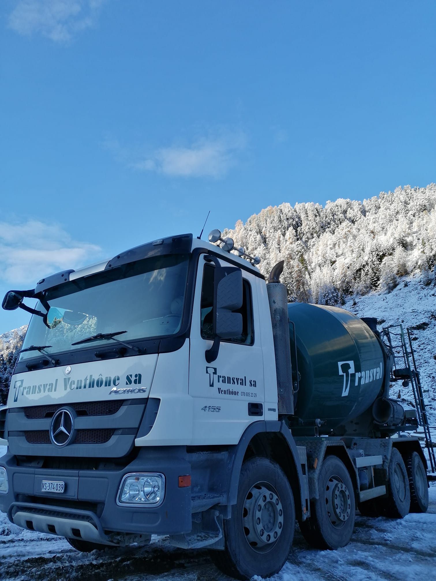 Un camion Mercedes Benz est garé dans la neige devant une montagne enneigée.