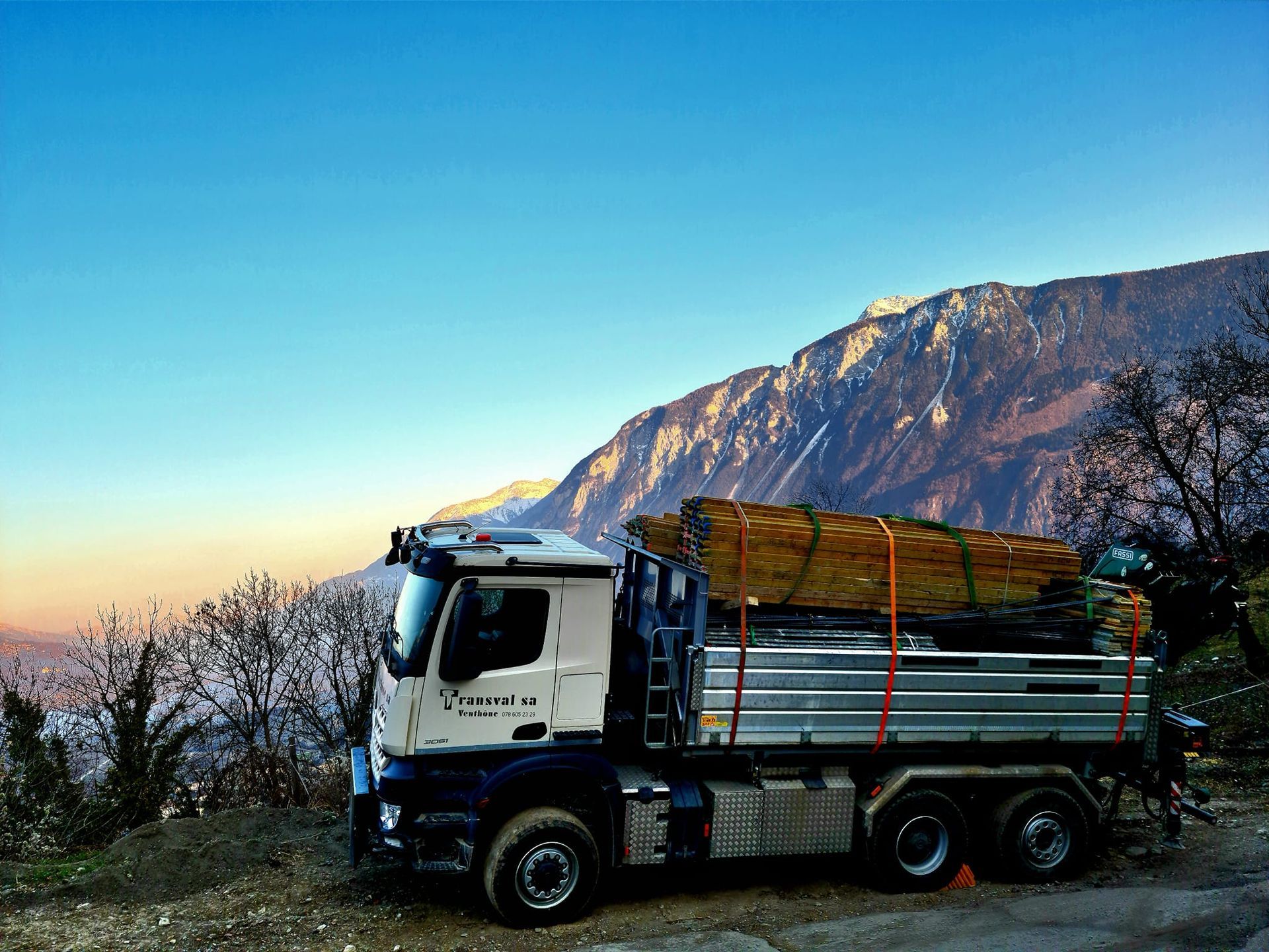 Un camion est garé sur le bord de la route avec une montagne en arrière-plan.