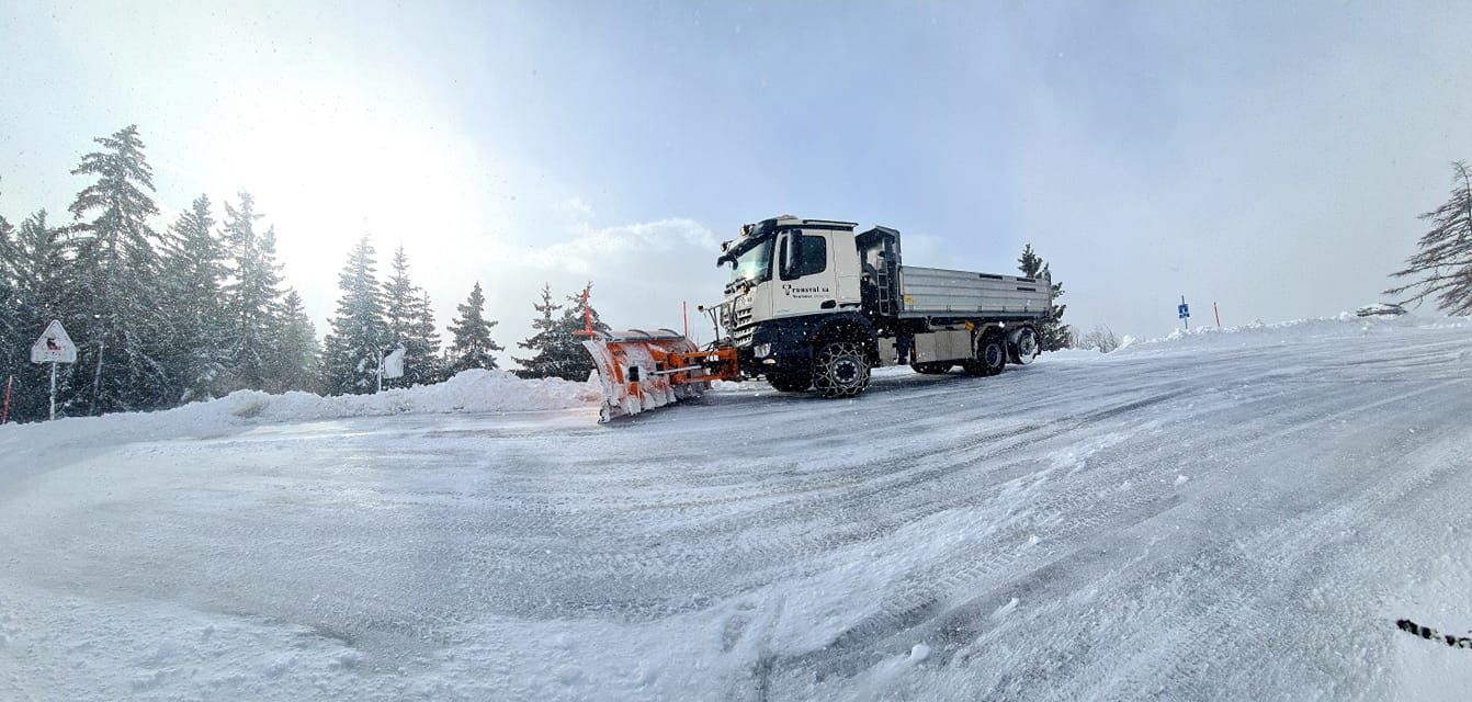 Un chasse-neige roule sur une route couverte de neige.