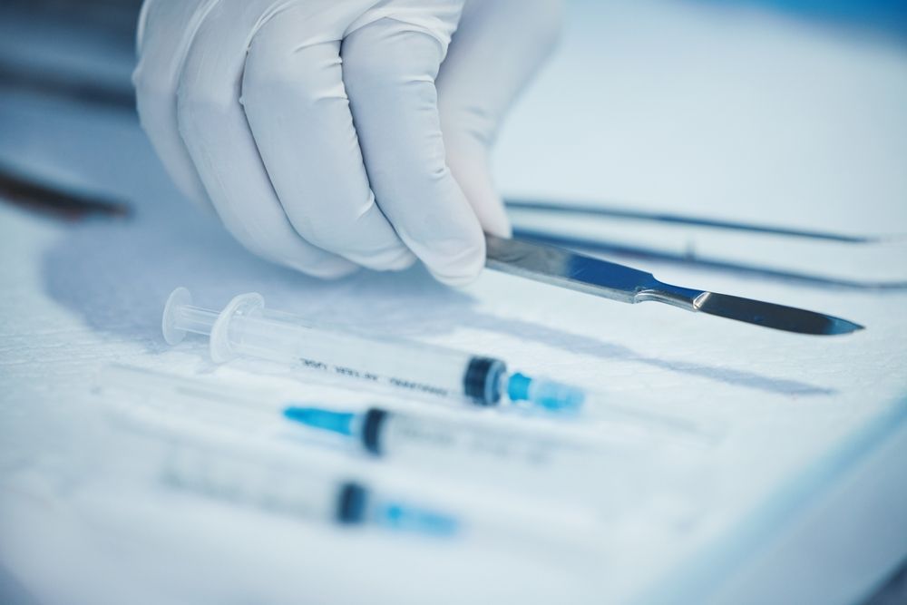 Gloved hand holding a syringe beside other medical syringes on a sterile surface