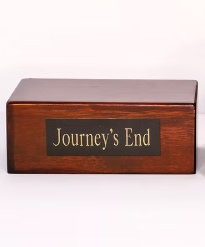Silver paw-print cremation urn with a red rose beside it on a wooden surface