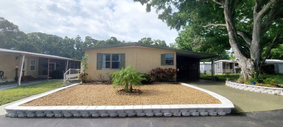 Mobile home with a rounded front planter bed and trees in the yard