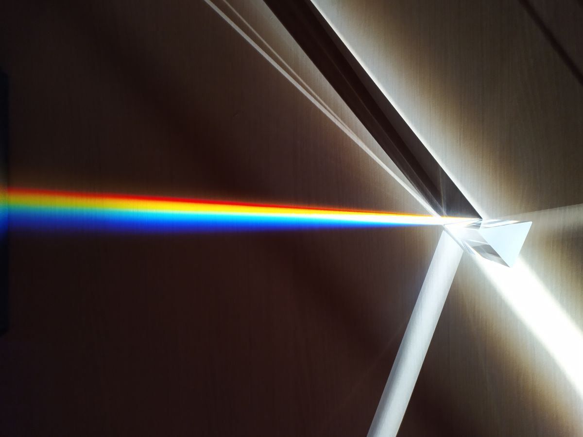 Rainbow beam of light splitting through a bright prism against a dark background