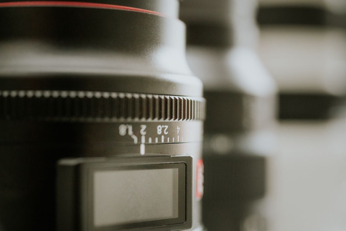 Close-up of a camera lens with red accent ring and blurred background