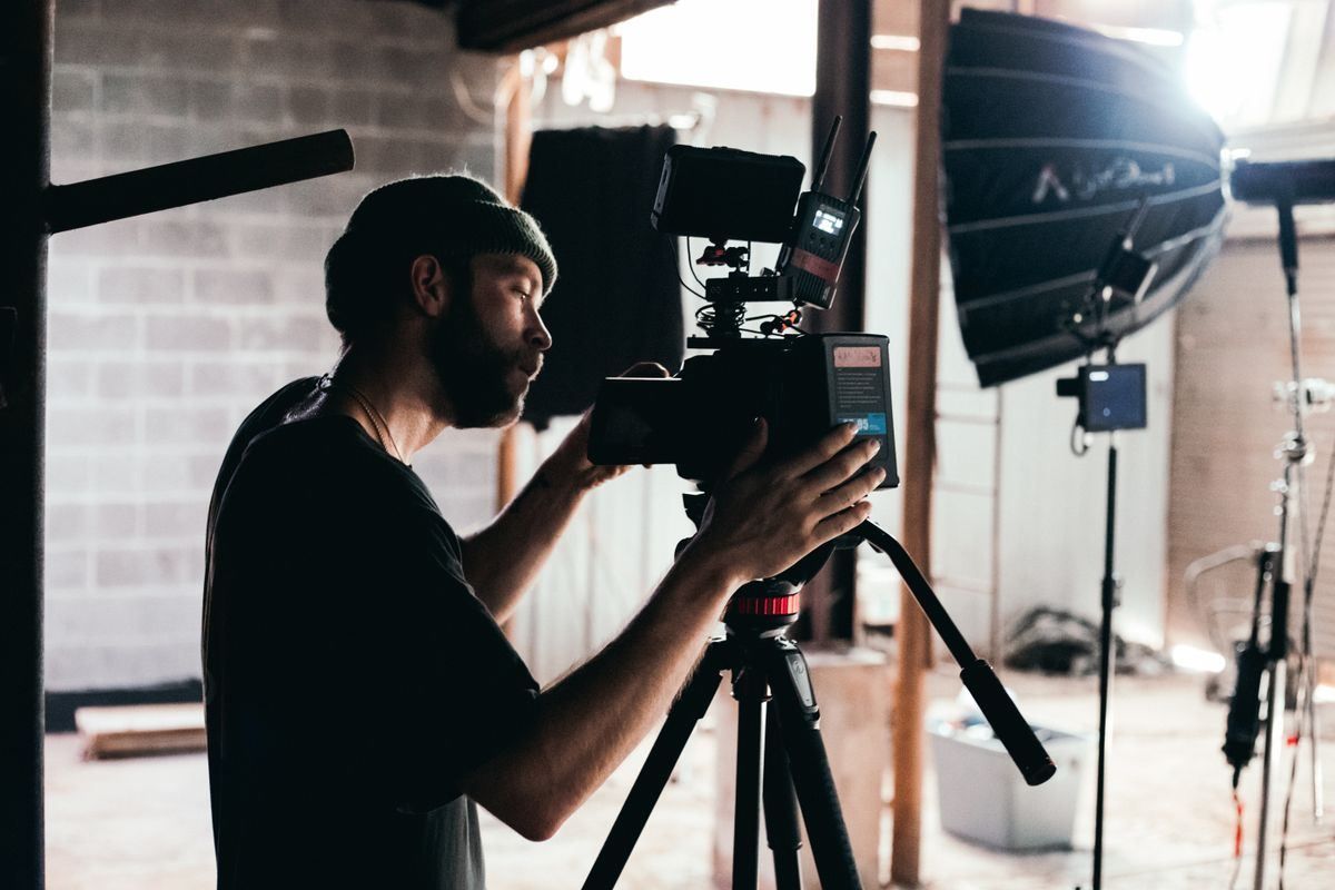 Photographer adjusting a camera on a tripod in a studio with lighting equipment