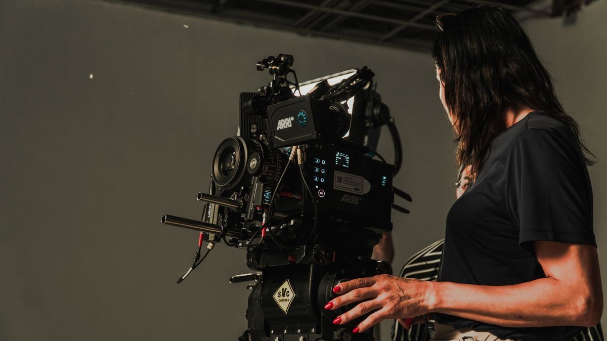Photographer adjusting a camera on a tripod in a studio with lighting equipment