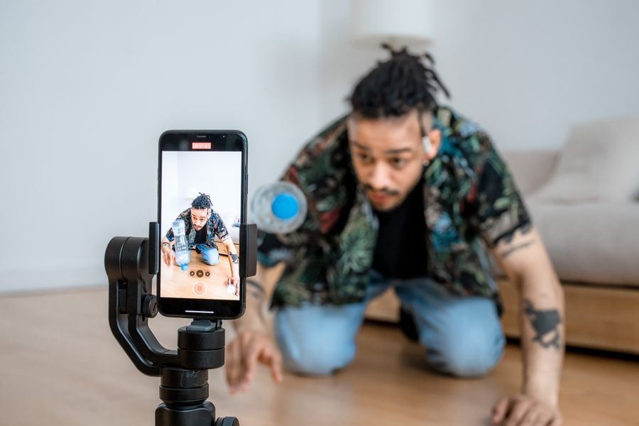 Smartphone on tripod filming a person kneeling on the floor in a room