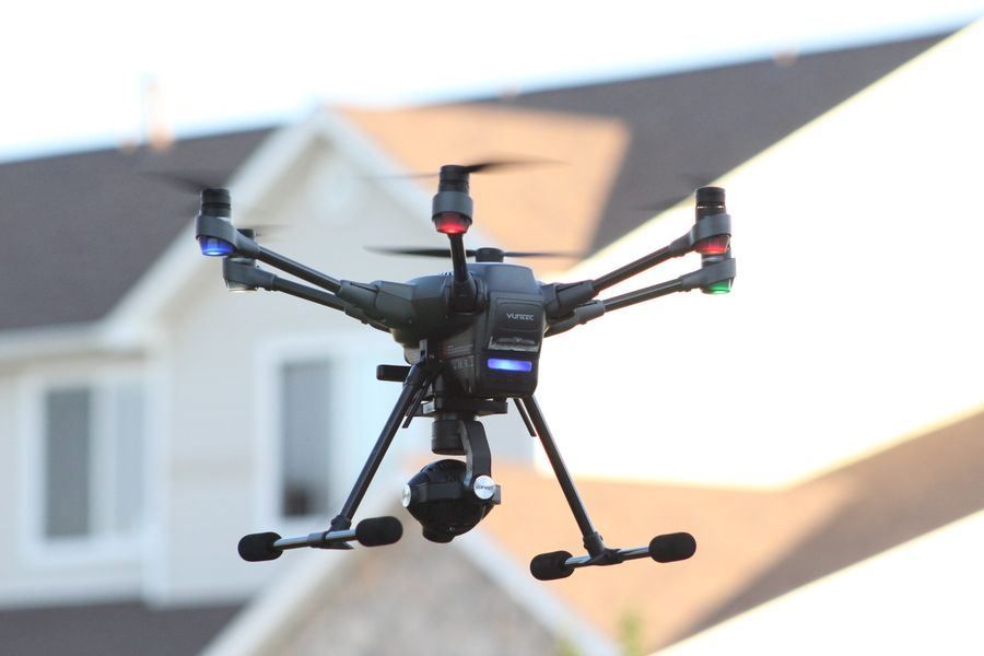 Black quadcopter drone hovering in front of a house exterior