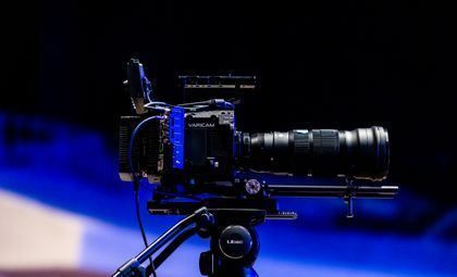 Professional camera on tripod against a dark blue-lit background