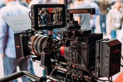 Professional video camera setup with external monitor at a public event