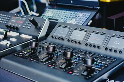 Professional audio mixing console with knobs, sliders, and illuminated controls in a studio.
