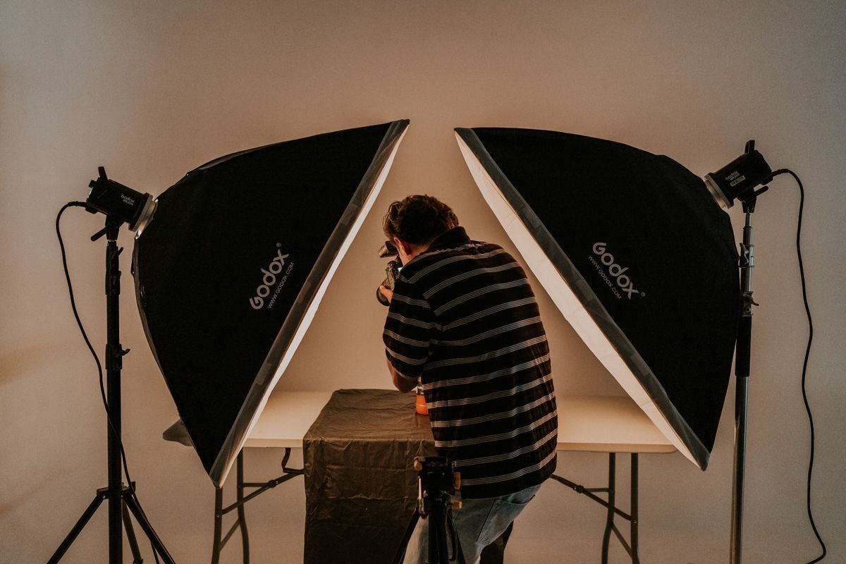 Person setting up a product shoot between two large studio softbox lights