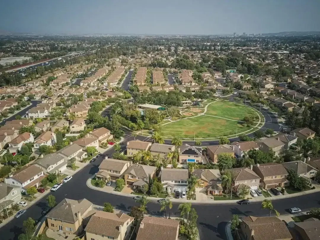 Aerial view of a suburban neighborhood with a large green park at the center