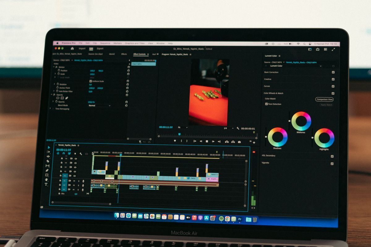 Laptop screen showing a video editor with a preview, timeline, and color wheels