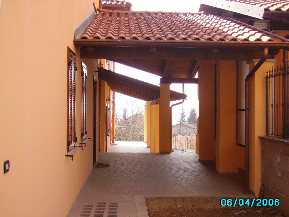 Passaggio coperto con pareti arancioni, tegole in terracotta e travi in legno marrone.