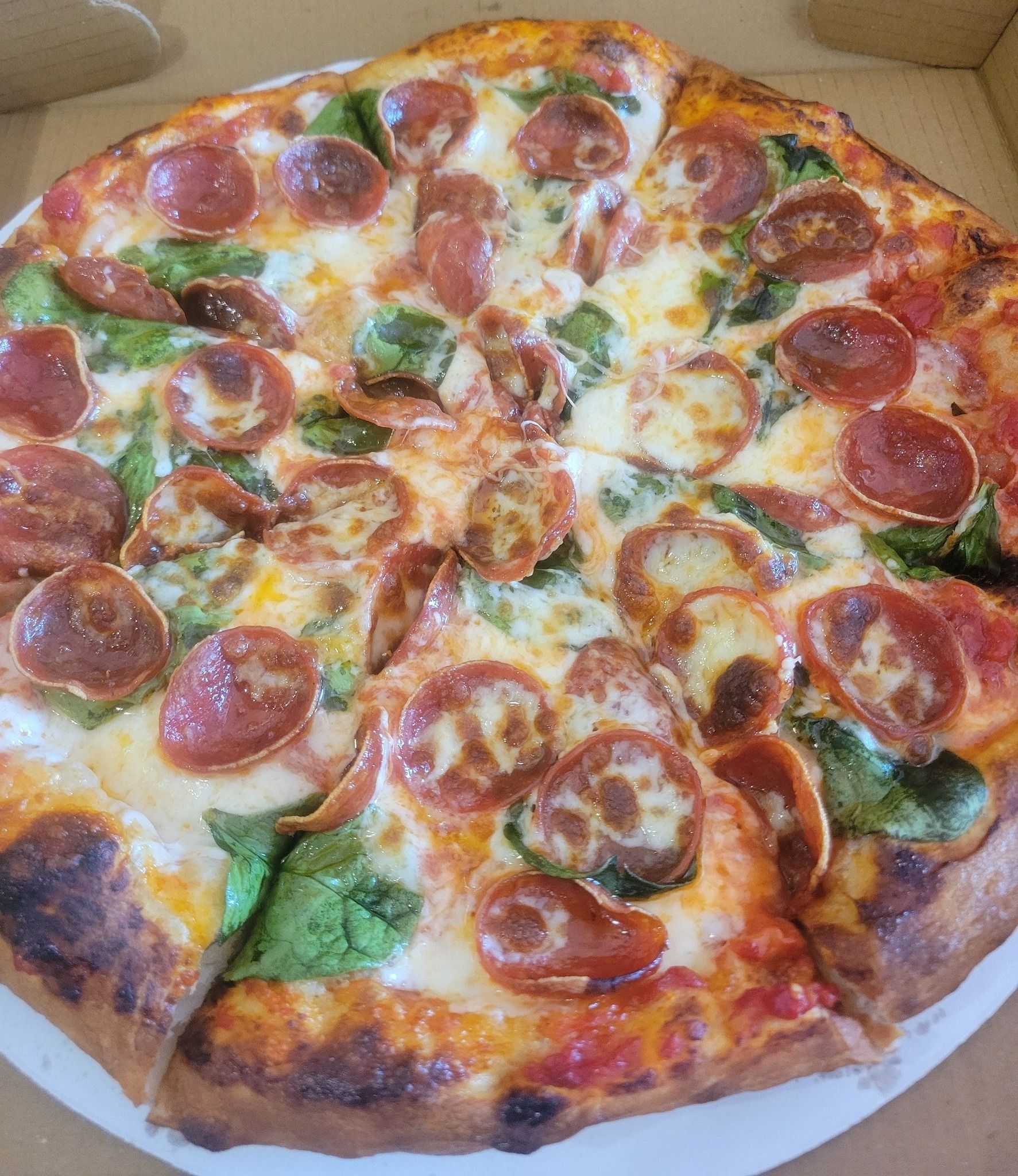 Pepperoni pizza with green peppers and melted cheese in a cardboard box
