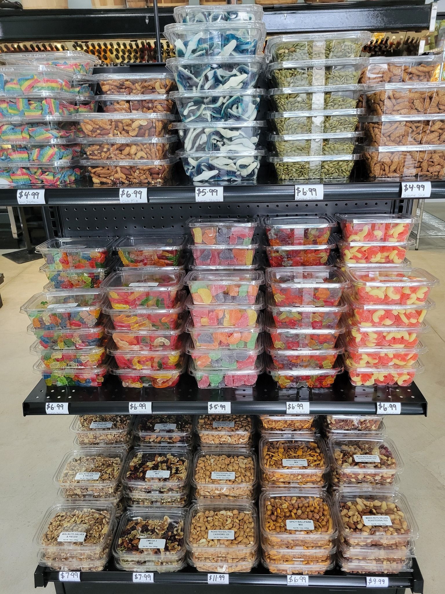 Store shelf stocked with rows of packaged snacks and fresh produce in clear plastic containers.