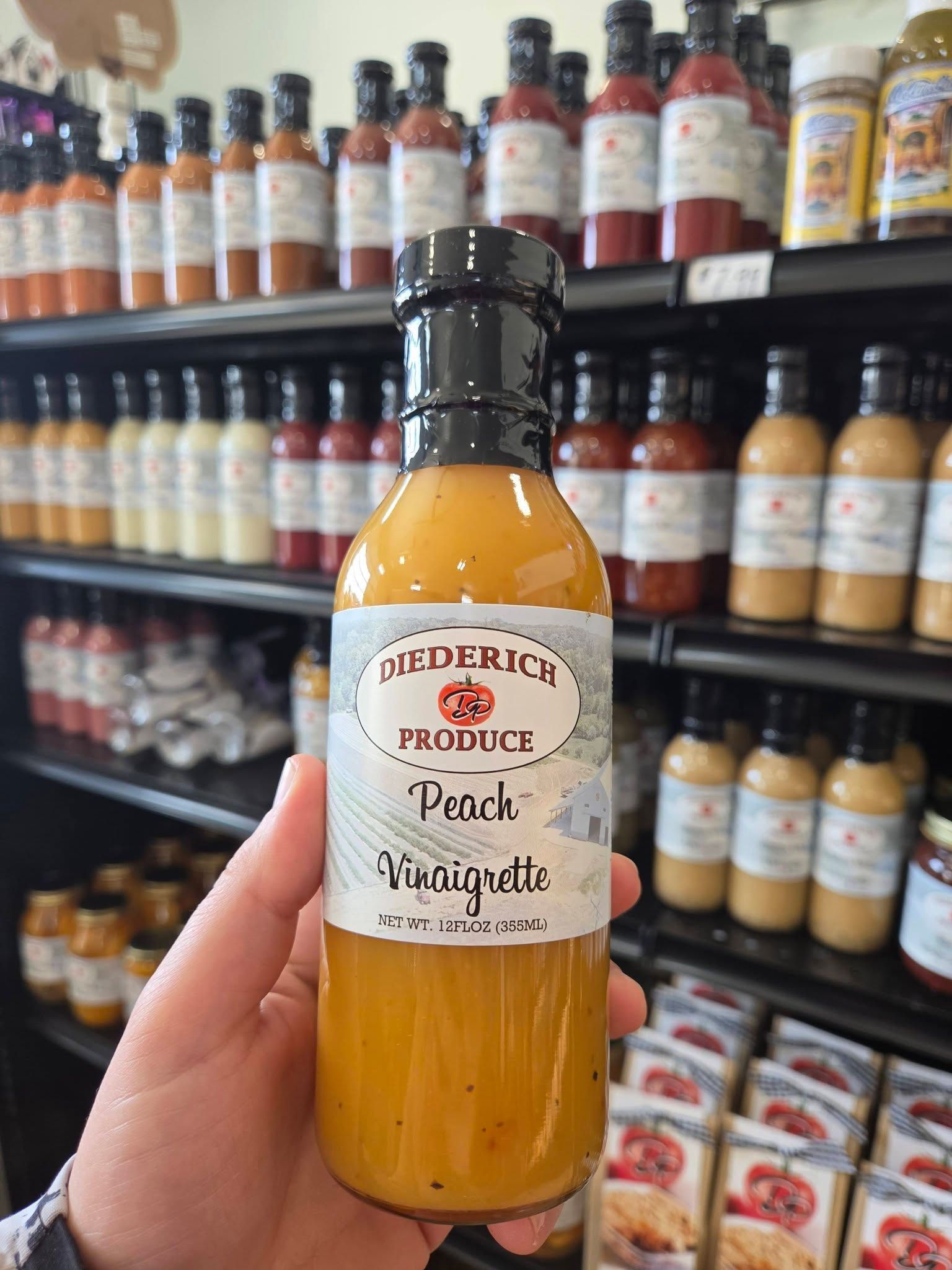 Hand holding a bottle of Pomegranate Ponzu in front of a grocery shelf of sauces and dressings
