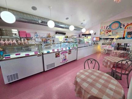 Pastel pink ice cream shop interior with display cases, seating, and checkered tables
