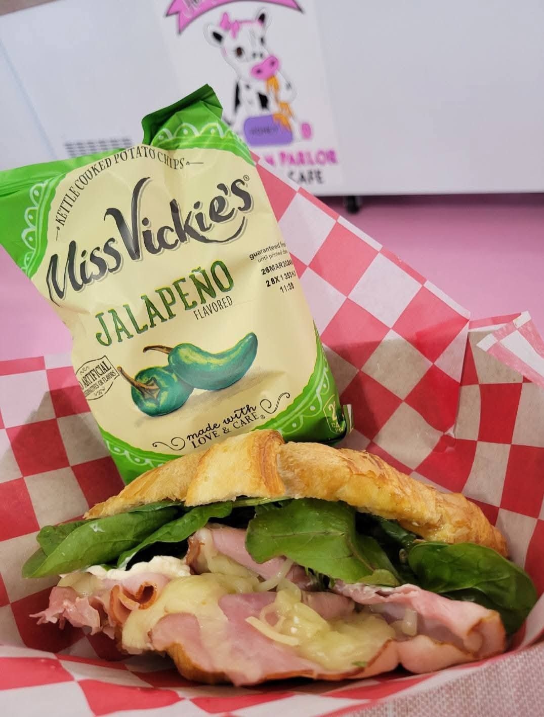 Sandwich in red check paper with Miss Vickie’s jalapeño chips bag behind it