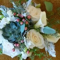 White rose bouquet with greenery, pink berries, and lace accents on a brown textured background