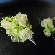White rose corsages with pale green accents on a black background