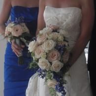Bride in white dress holding a cascading bouquet of cream and blue flowers.