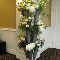 Tall gray cone flower arrangement with white and pale pink blooms in a hallway corner