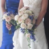 Bride in white dress holding a cascading bouquet of cream and blue flowers 
