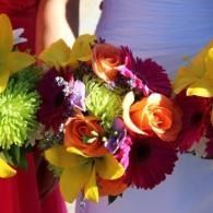 Colorful bouquet of orange, yellow, and purple flowers against a soft blue background