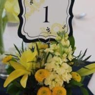 Floral arrangement with yellow and white flowers beneath a table number 1 sign