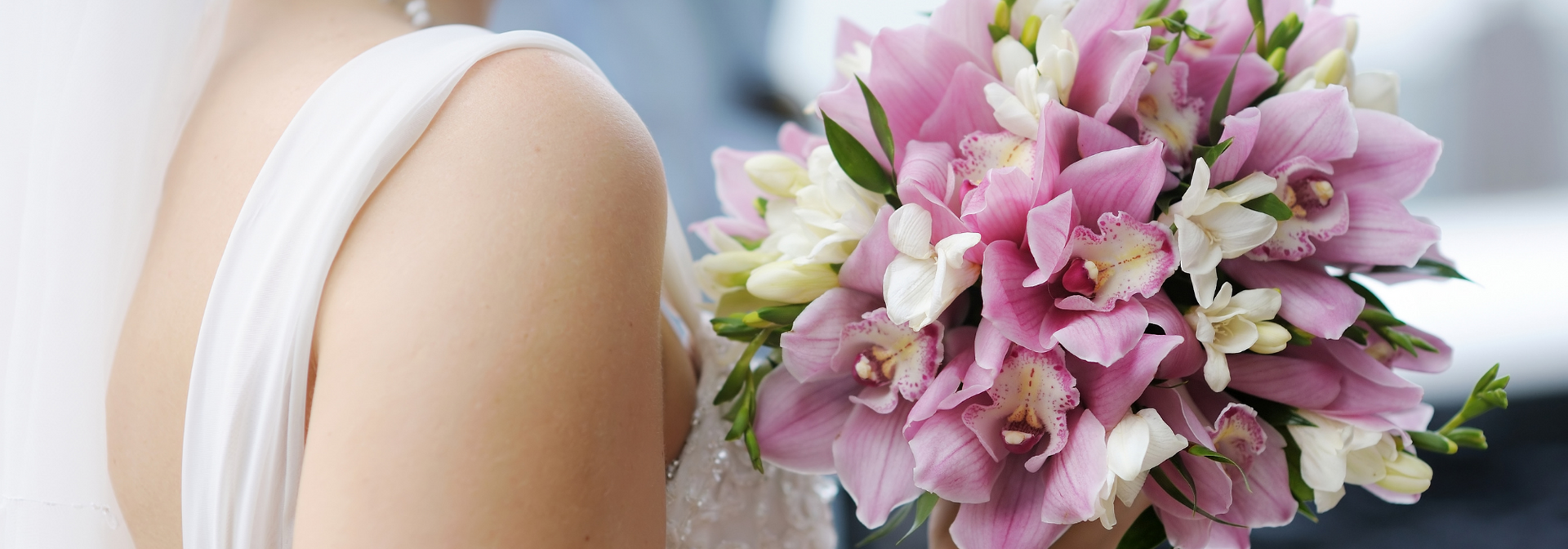 Bride holding a pink and white bouquet against a white dress
