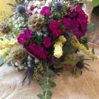 Bouquet of magenta, white, and green flowers arranged on a beige furry surface