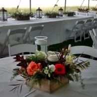 Table centerpiece with red and white flowers in a jar on a banquet table outdoors