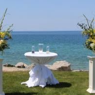 White round table set on a grassy seaside lawn beside blue ocean water