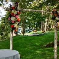 Flower-decorated arch in a green park with tables and trees in the background