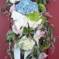 White and pastel floral arrangement with blue hydrangeas and pink accents on a burgundy background