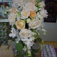 White and cream roses with greenery in a tall vase on a checkered tablecloth