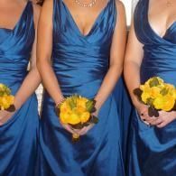 Bridesmaids in blue satin dresses holding yellow bouquets at a wedding ceremony